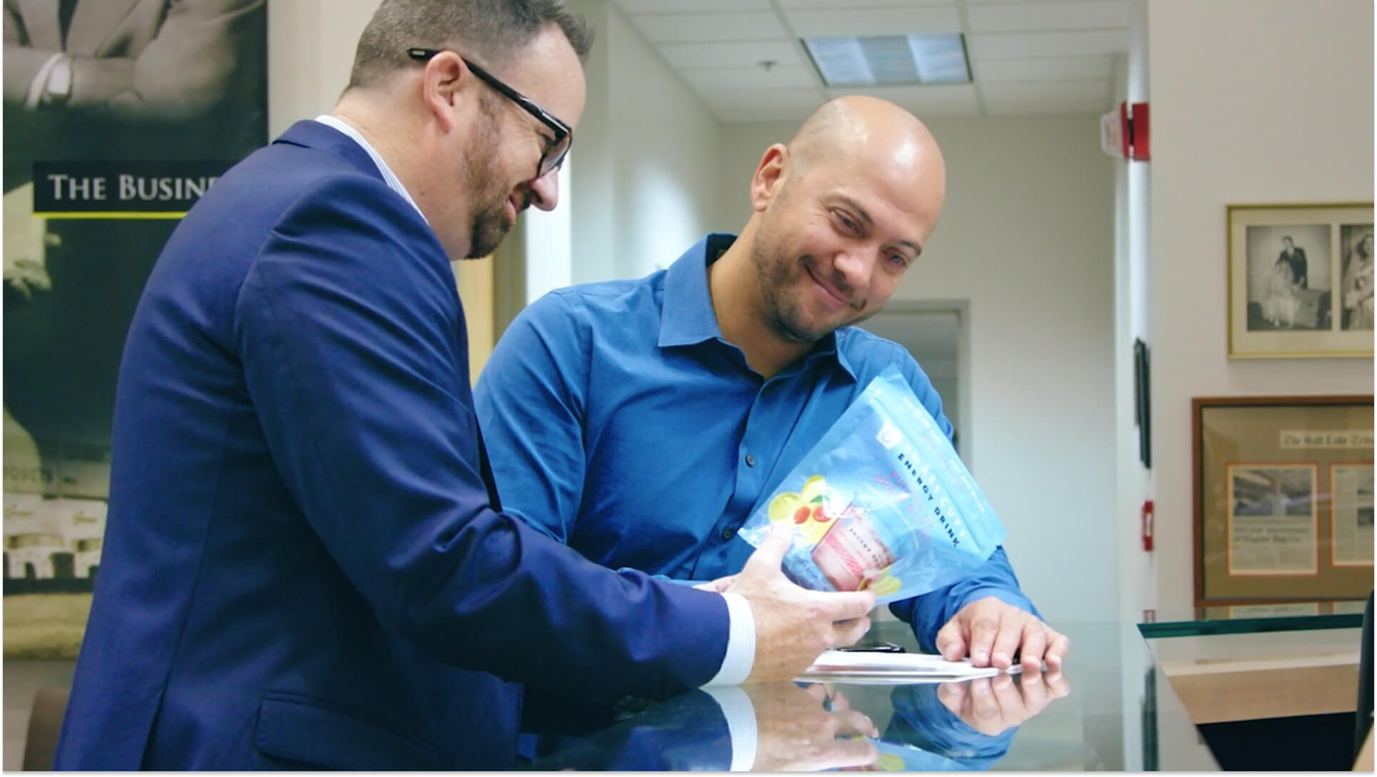 Business professionals reviewing flexible packaging pouch sample with colorful fruit graphics in office setting